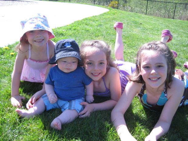 Four children laying in grass smiling into camera