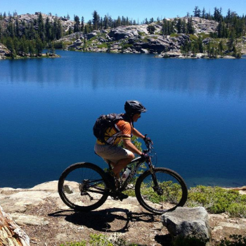 Cyclist passing by a lake on Pines to Mines trail