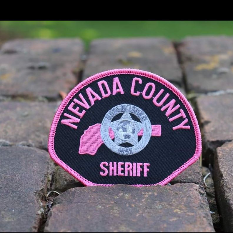 A Nevada County Sheriff patch with pink lettering and a pink Nevada County shape