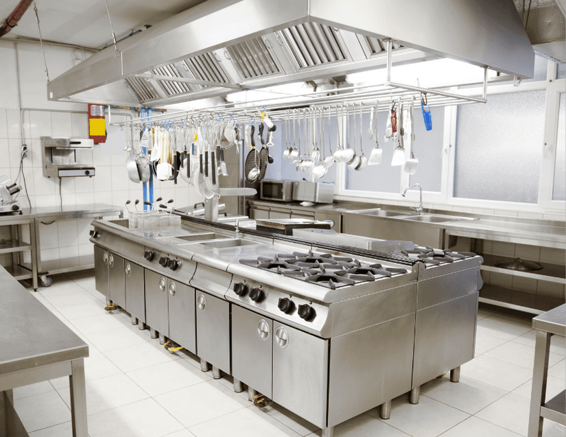 Industrial kitchen with steal appliances in an island and utensils hanging over the island.
