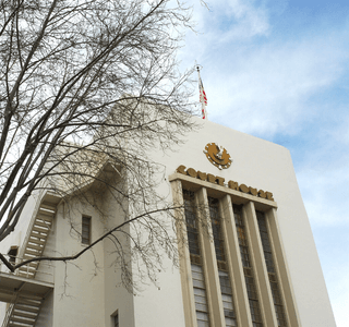 The Nevada City Courthouse surrounded by tree limbs with a blue sky in the background