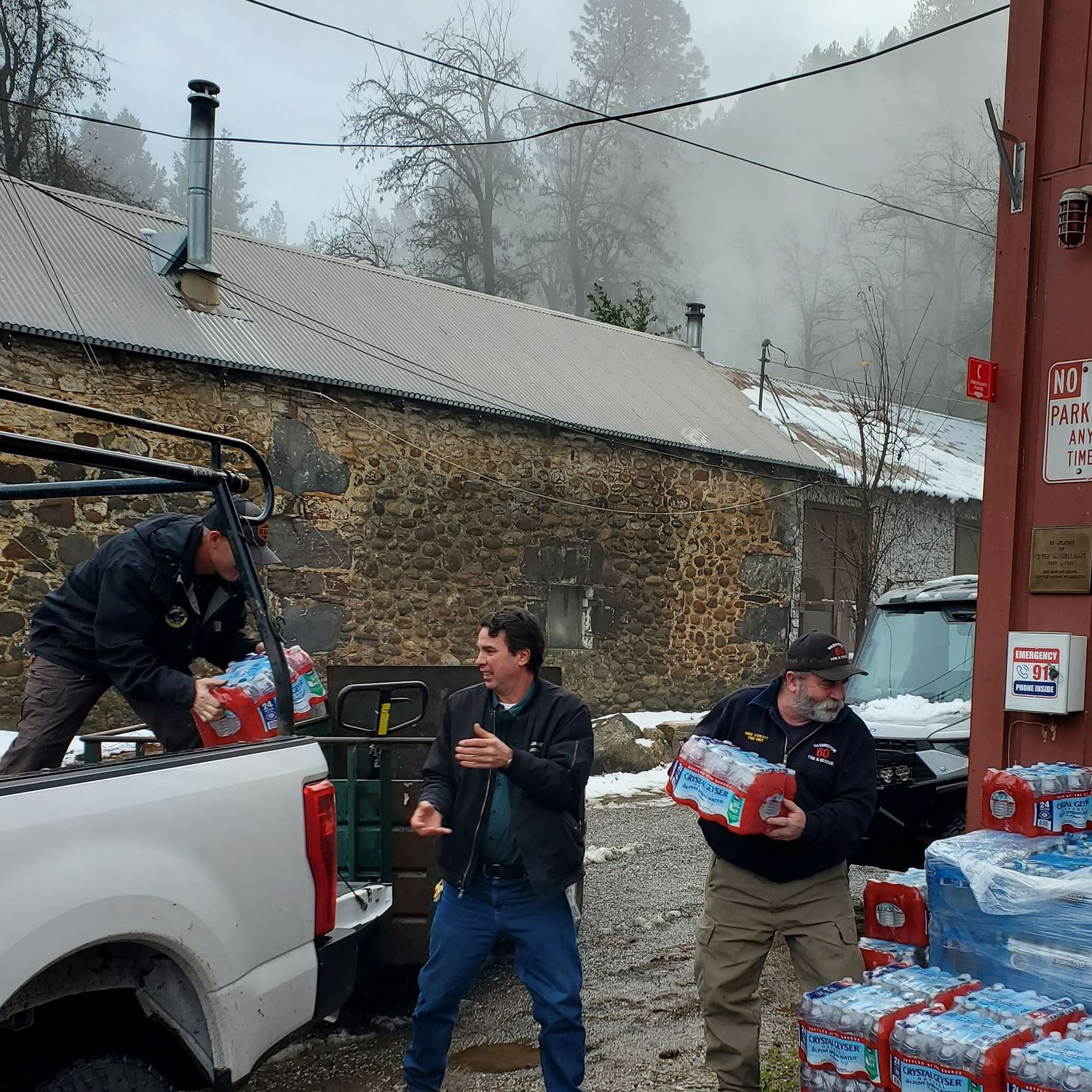 Two people unload and stack bottled water from a truck