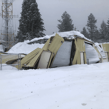 A metal building collapses under the weight of heavy snow