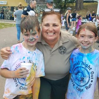 Sheriff Shannan Moon embraces two children wearing National Night Out t-shirts covered in paint