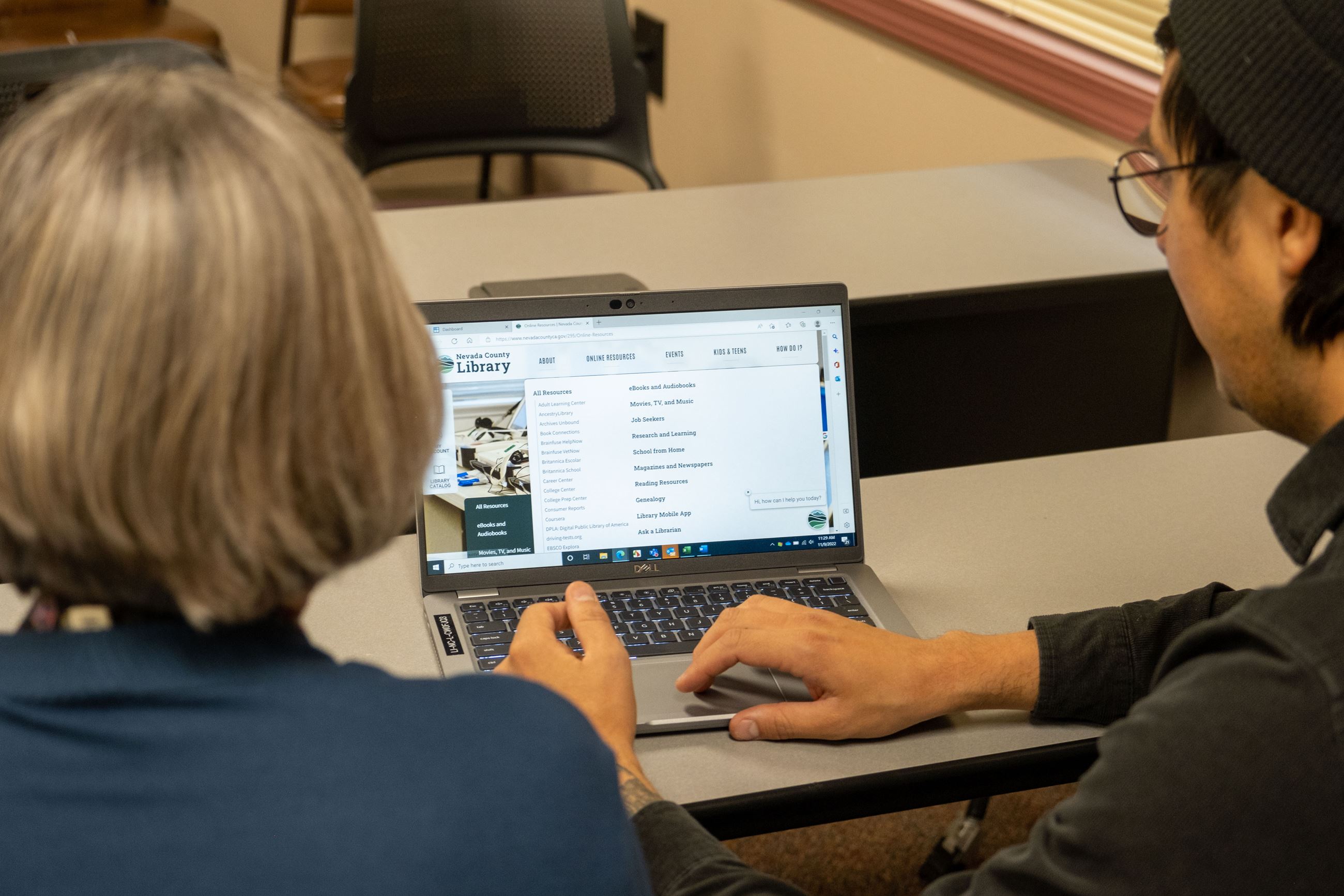 Two people at a computer looking at a website 